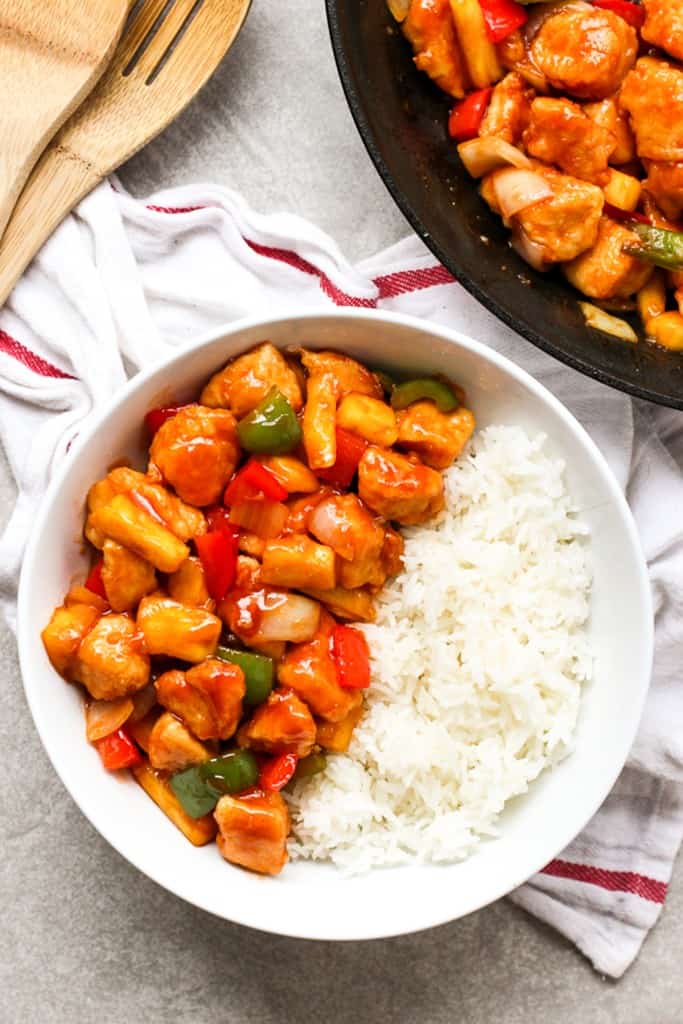 Top down view of a bowl of sweet and sour chicken with rice