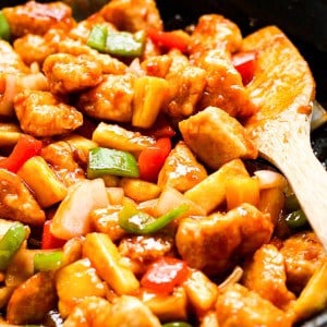 CLoseup of sweet and sour chicken with wooden spatula on the side