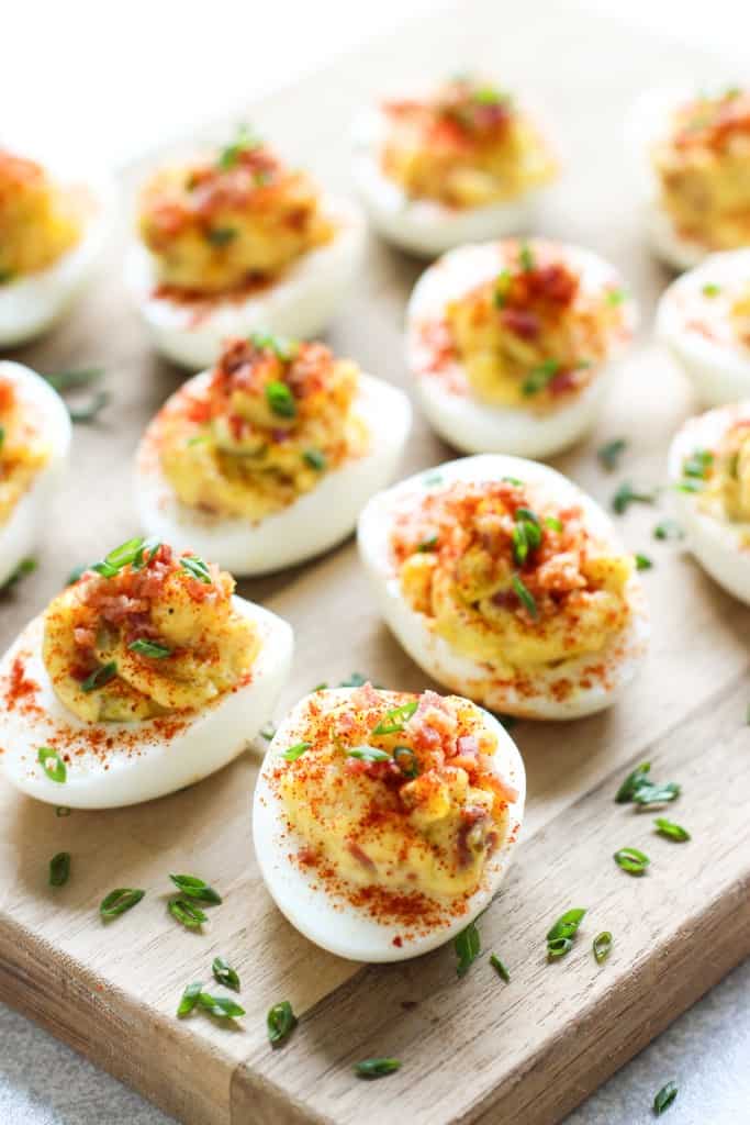 Deviled eggs with bacon topped with paprika dusting and chives