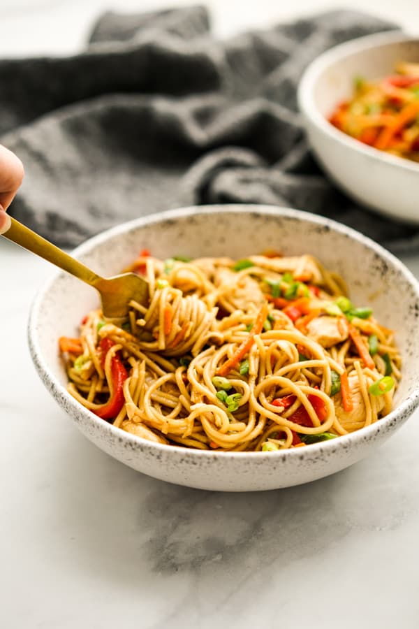 Chicken Lo Mein on a bowl with chopsticks picking the noodles