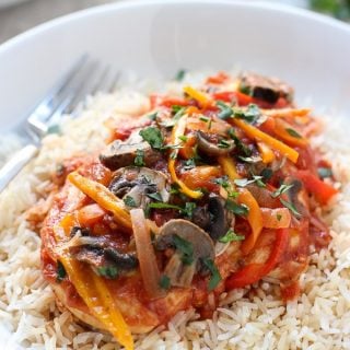 Slow Cooker Tomato and Herb Chicken with rice on a plate with a fork on the background