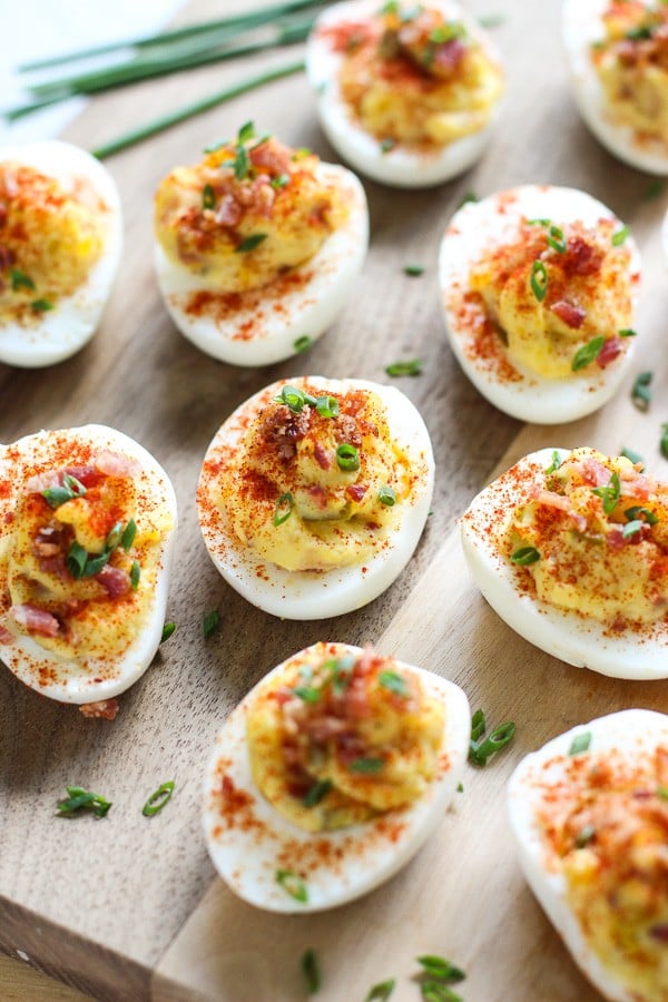 Bacon Deviled Eggs on a wooden board with chives in the background