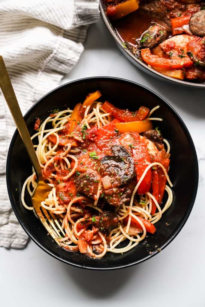 A bowl of spaghetti pasta topped with chicken cacciatore