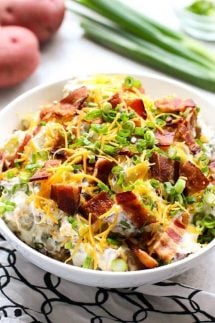 Loaded Baked Potato Salad with green onions and red potatoes behind it