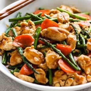 a bowl of chicken, asparagus and carrots stir fry in a sticky sauce