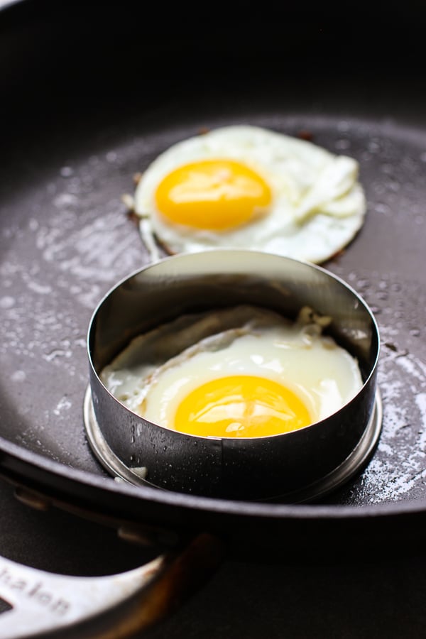 Frying eggs using an upside down cookie cutter to shape the eggs round