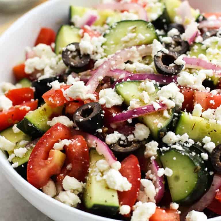 a bowl of cucumber salad with tomatoes, red onions, black olives and feta cheese