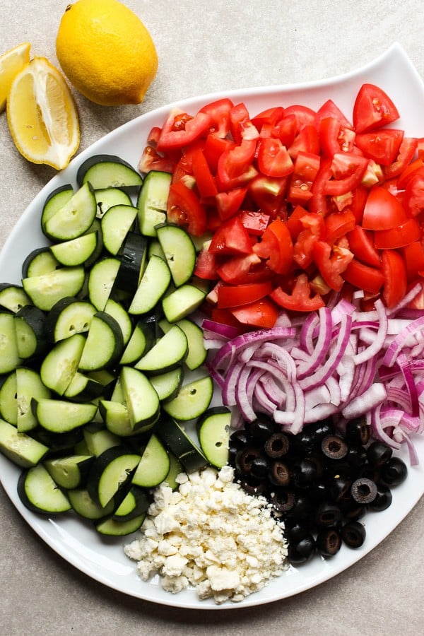 A large plate filled with tomatoes, cucumber, onions, olives and feta cheese