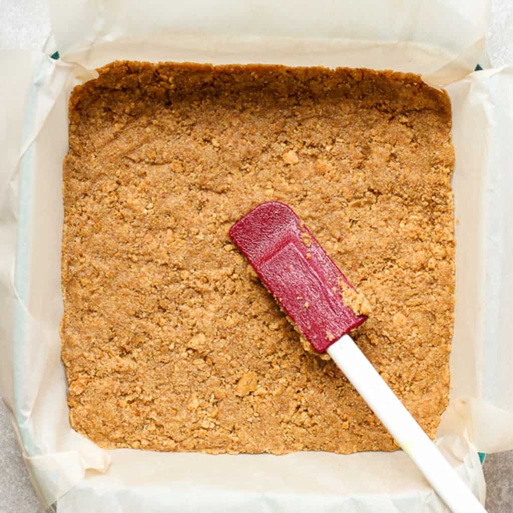 Pressing down graham cracker mixture onto dish