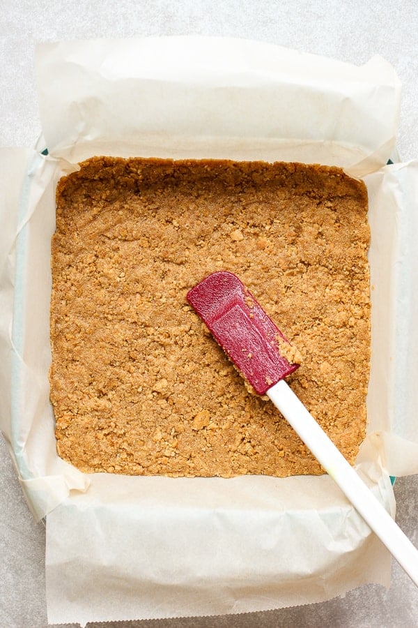 Pressing down crushed graham crackers on a casserole dish