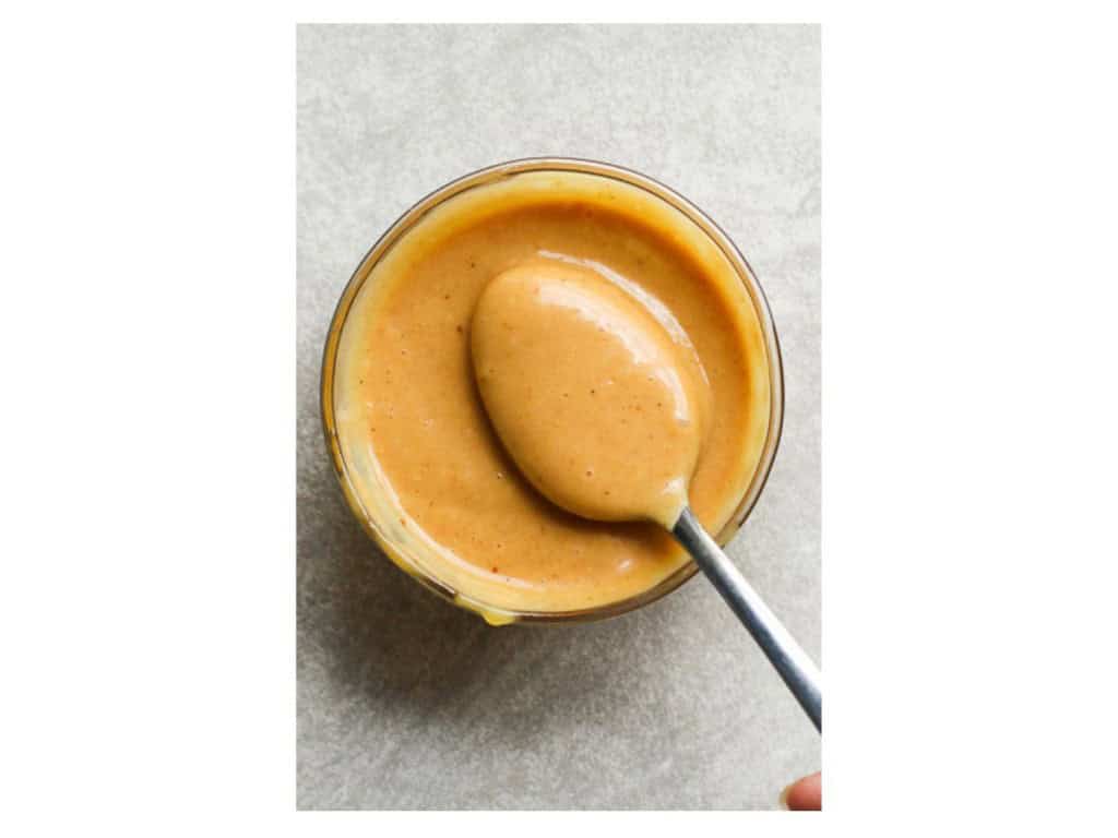 Spoon scooping into a small bowl of honey mustard bbq dressing