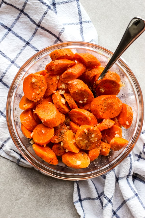 A bowl of raw carrots tossed with garlic, honey, butter, salt and pepper