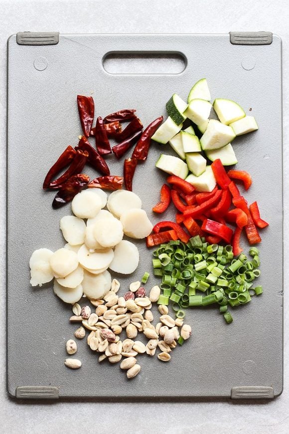 Red chillies, water chestnuts, peanuts, zucchini, bell peppers and green onions on a cutting board
