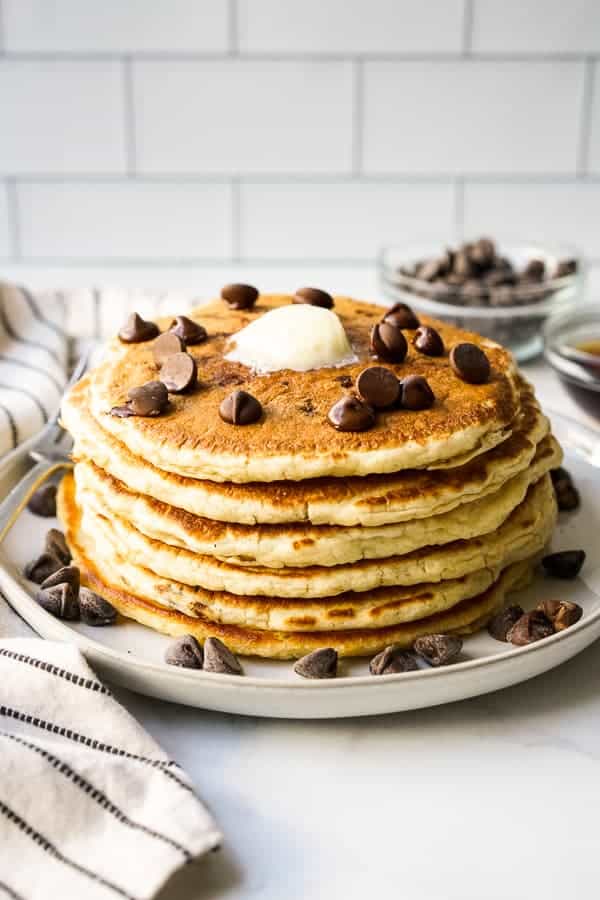 A stack of pancakes on a plate with lots of chocolate chips