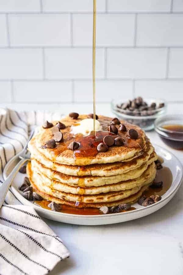 Drizzling maple syrup onto chocolate chip pancakes