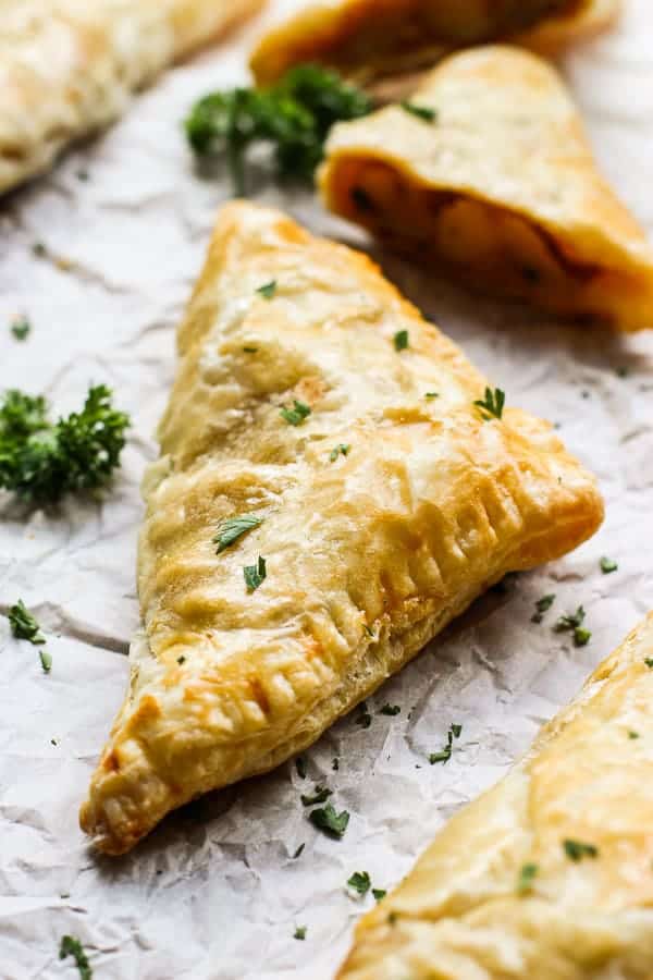 A piece of Malaysian Curry Puff with a few pieces cut into half in the background