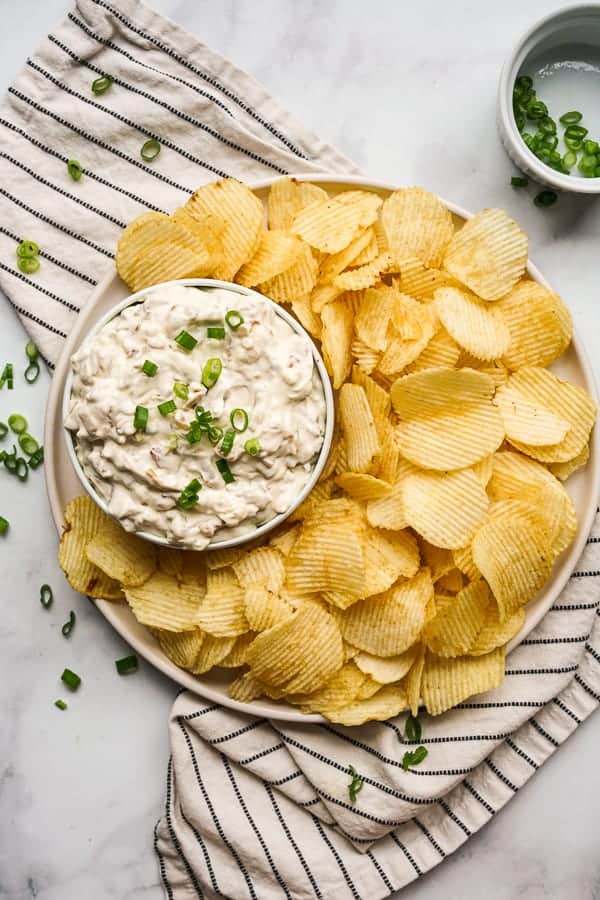 Top down view of a bowl of Caramelized Onion Dip with potato chips