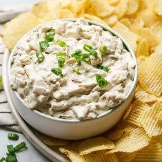 A bowl of Caramelized Onion Dip with potato chips on the side