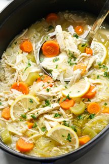 a pot of chicken soup loaded with lemon, carrots, chicken and rice