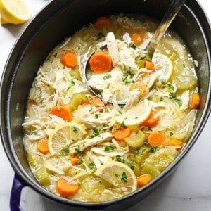a pot of chicken soup loaded with lemon, carrots, chicken and rice