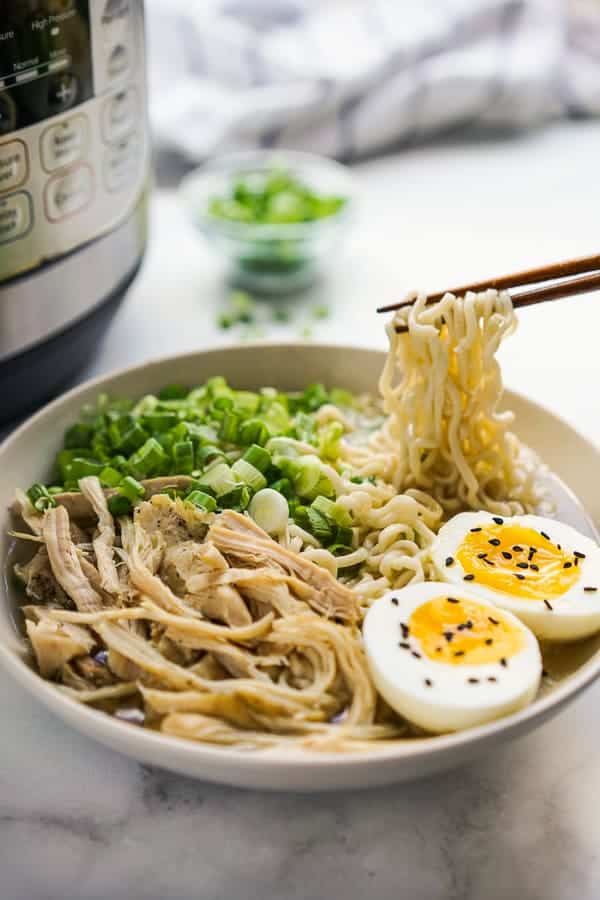 Picking up Instant Pot Ramen Noodles with chopsticks with an Instant Pot behind