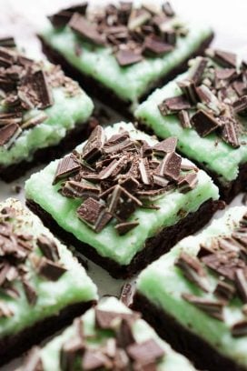 Closeup of chocolate brownies topped with green mint icing and Andes Mint pieces