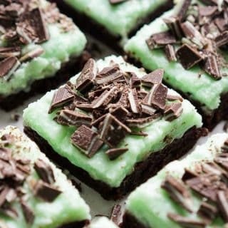 Closeup of chocolate brownies topped with green mint icing and Andes Mint pieces