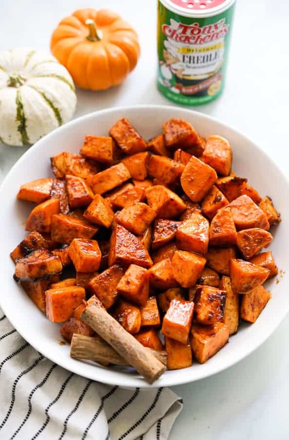 A bowl of Spicy Roasted Sweet Potatoes with spices in the background