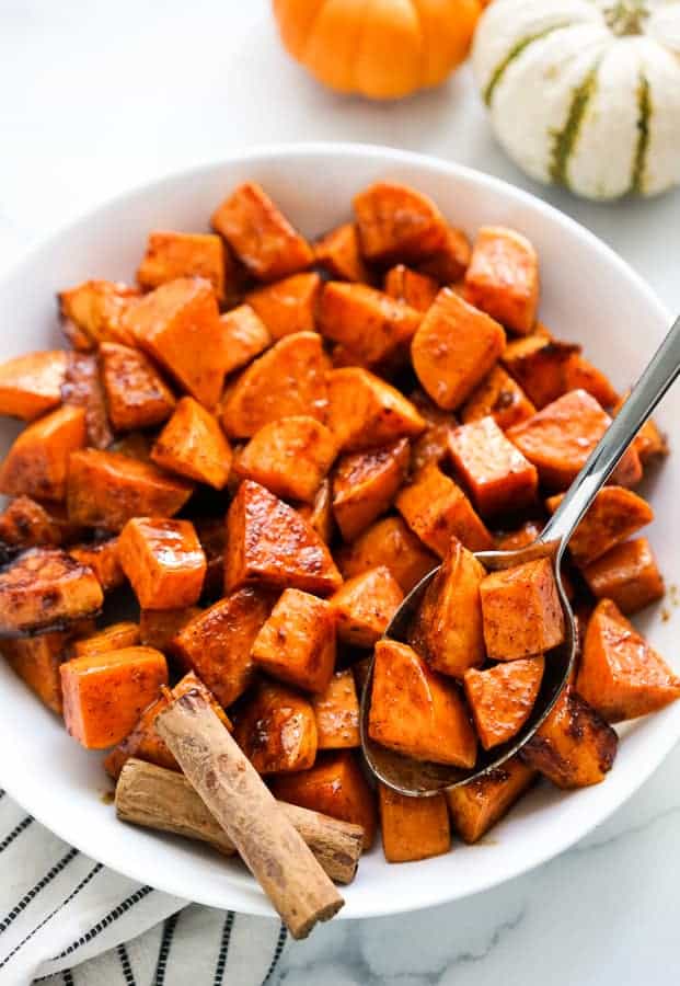 Using a spoon to scoop out some spicy sweet potatoes