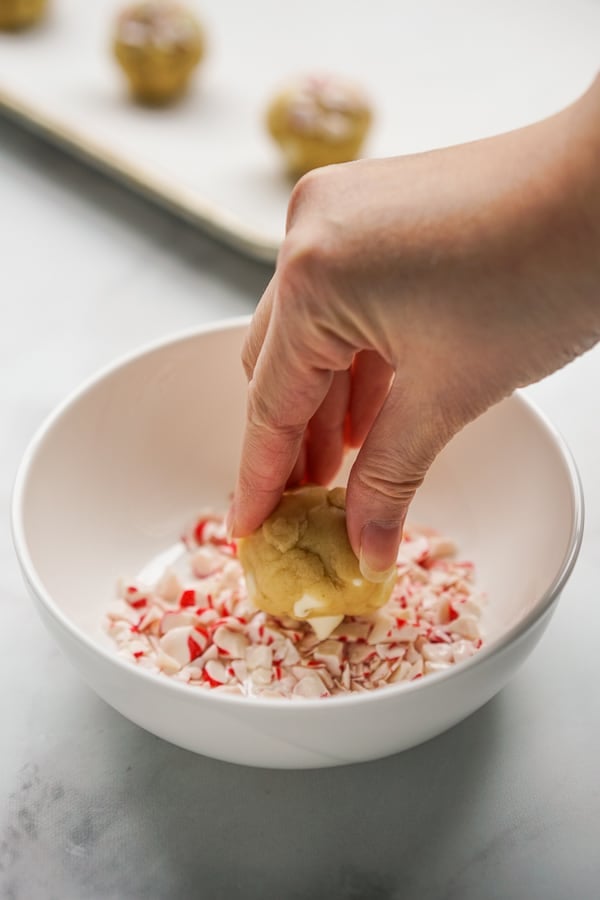 Dipping cookies dough ball into peppermint pieces
