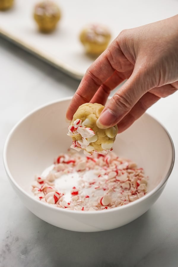 Dipping cookies dough ball into peppermint pieces