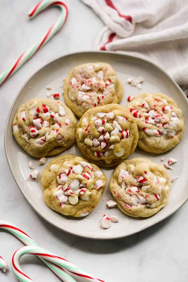 A plate of White Chocolate Peppermint Cookies with candy canes around it