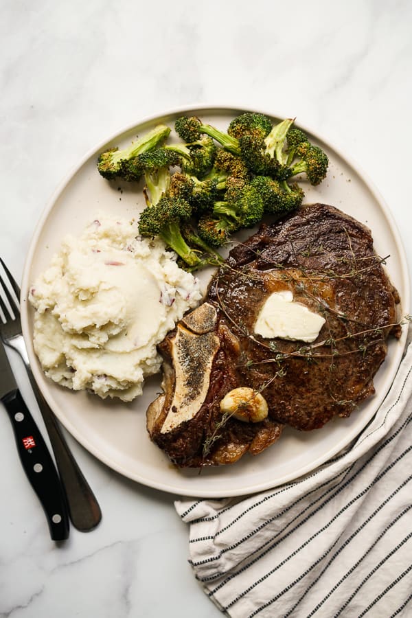 Top down view of a plate of steak with broccoli and mashed potatoes