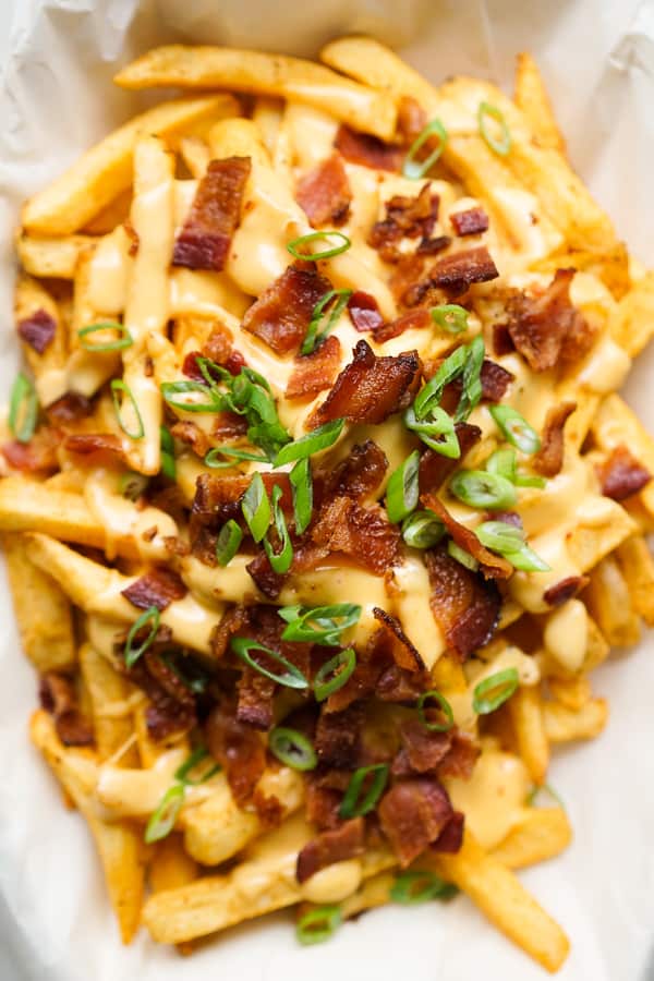 Baked fries topped with cheese sauce, bacon and green onions