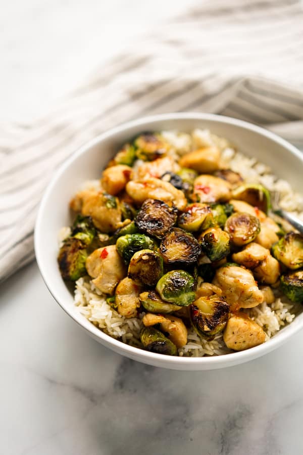 A bowl of brussels sprouts and chicken with rice, with a napkin in the background