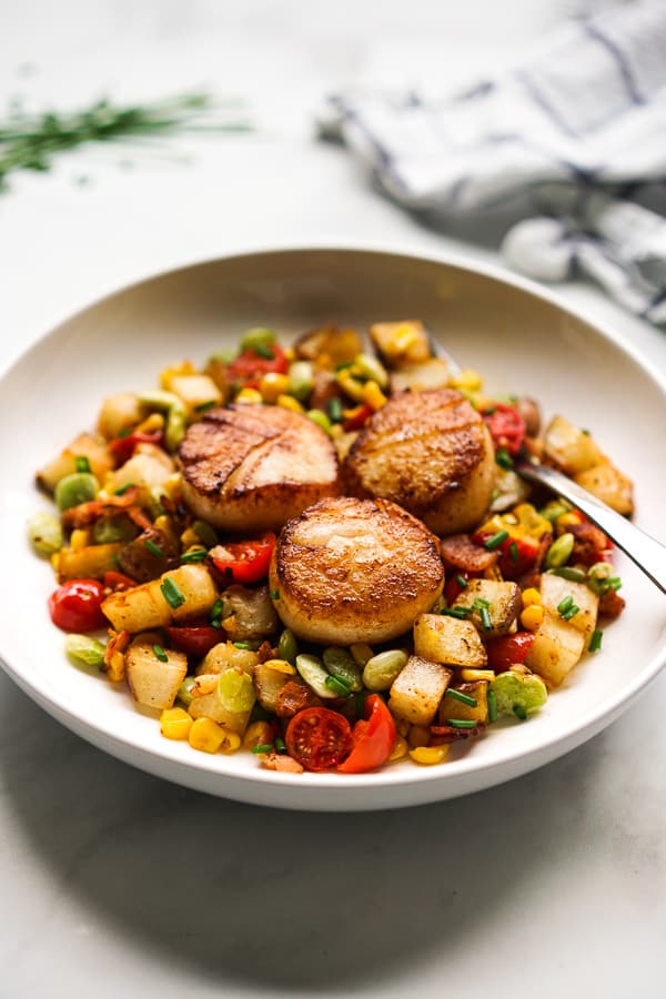 A plate of Garlic butter scallops and Succotash made with potatoes, corn, and lima beans