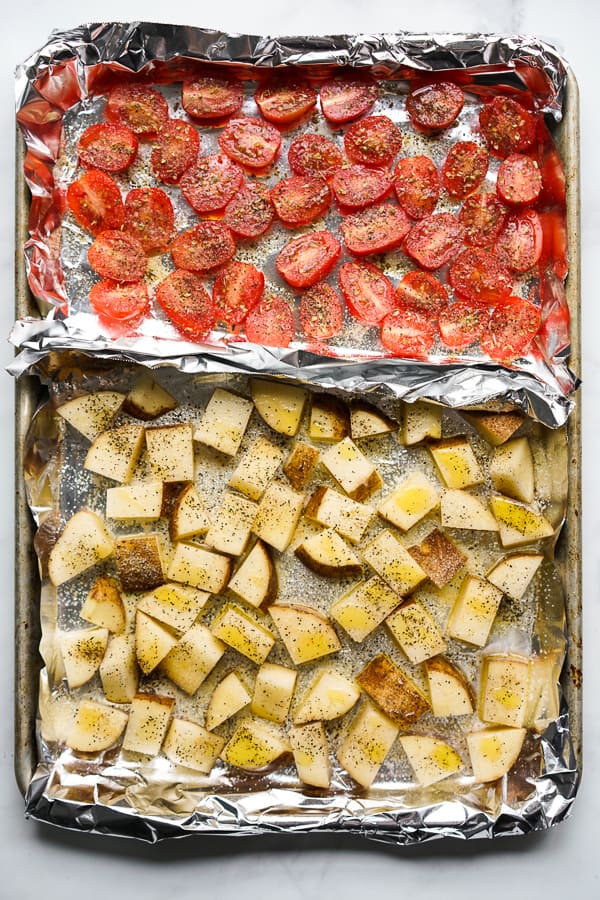 A sheet pan with roasted russet potatoes and roasted tomatoes