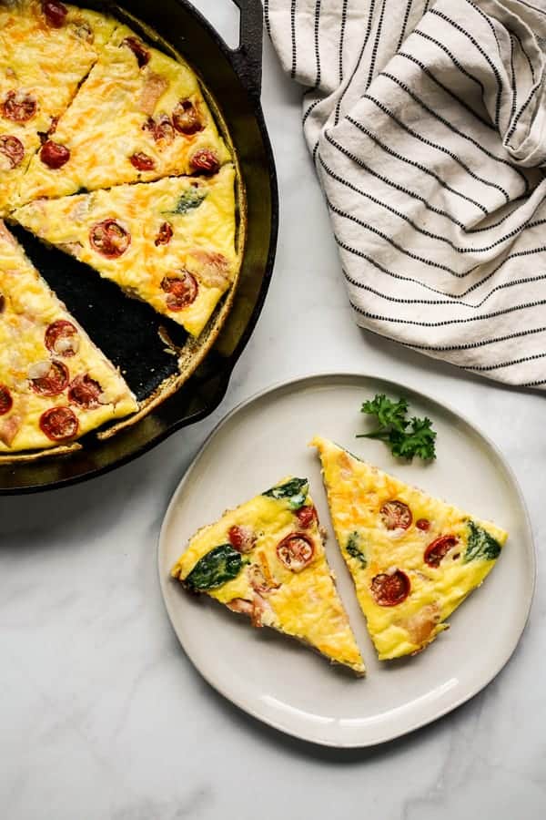 Frittata in a cast iron and a few sliced frittata on a plate