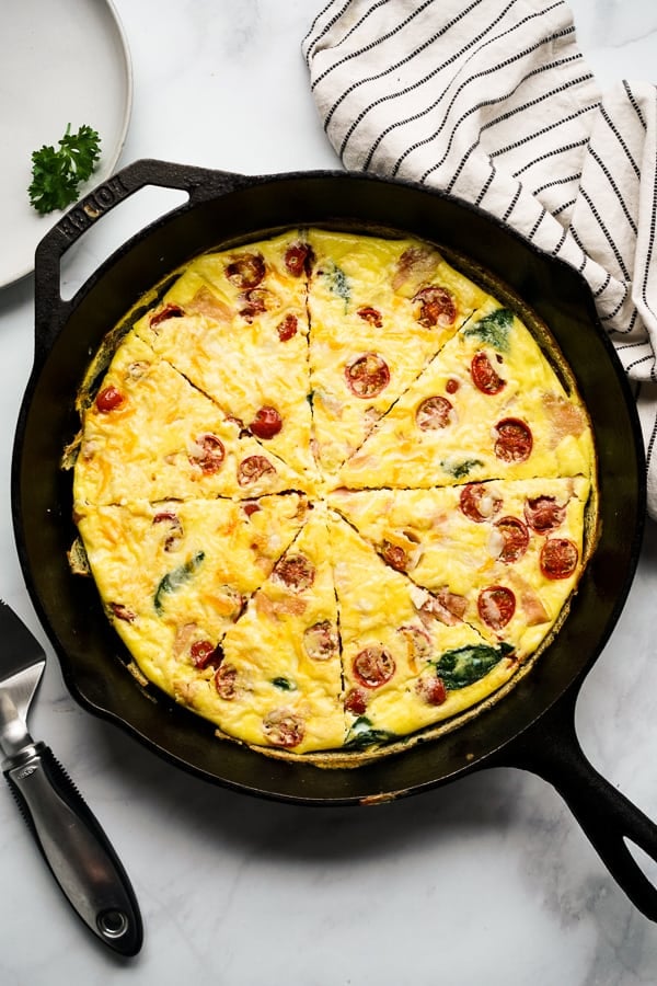 Easy Frittata Recipe with ham, spinach and tomato on a cast iron