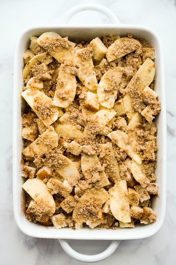 Sliced apple, egg mixture, French bread, and crumble topping in a casserole dish