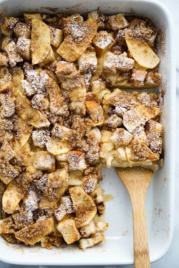 Using a spatula to lift up a square slice of Baked French Toast Casserole from a rectangular dish.