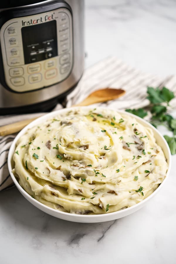 A bowl of garlic mashed potatoes with Instant Pot in the background