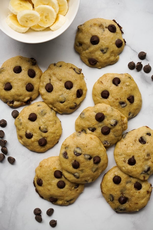 Cookies spread out on the counter with a bowl of sliced bananas