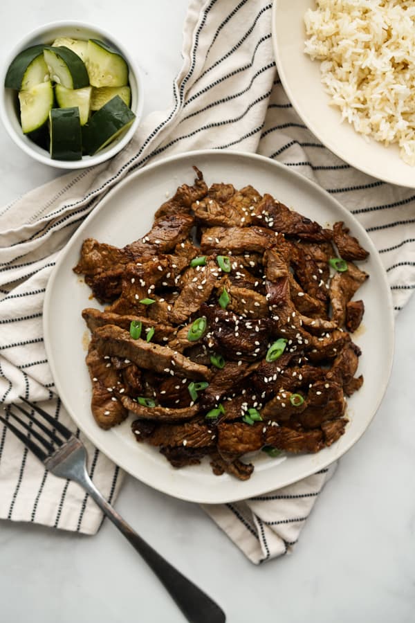 Top down view of Korean BBQ Beef Bulgogi with a plate of rice next to it