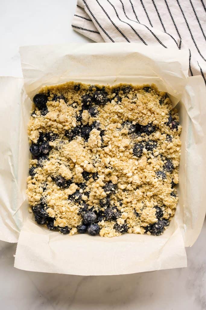 Unbaked blueberry crumble bars on a square dish