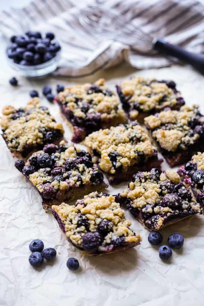 Nine square blueberry crumb bars placed on crinkled parchment paper