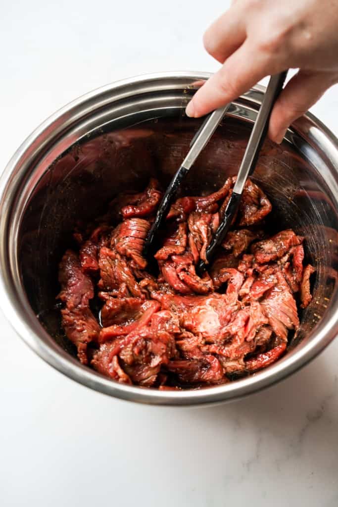 Marinating sirloin beef in bulgogi marinade in a large mixing bowl