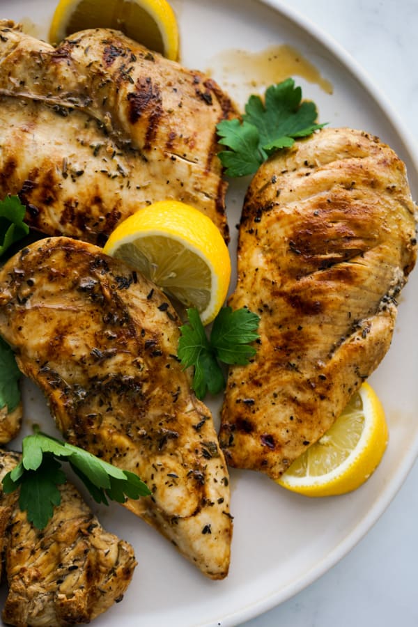 A plate of Lemon Balsamic Grilled Chicken with fresh lemons and parsley