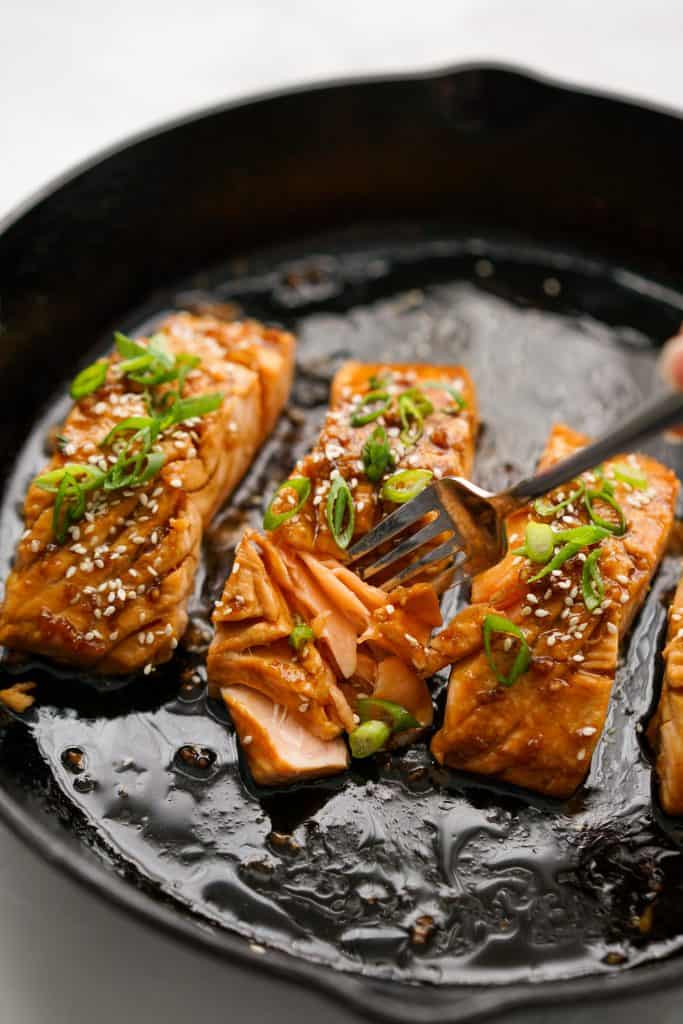 Cutting into a piece of pan fried teriyaki  glaze salmon