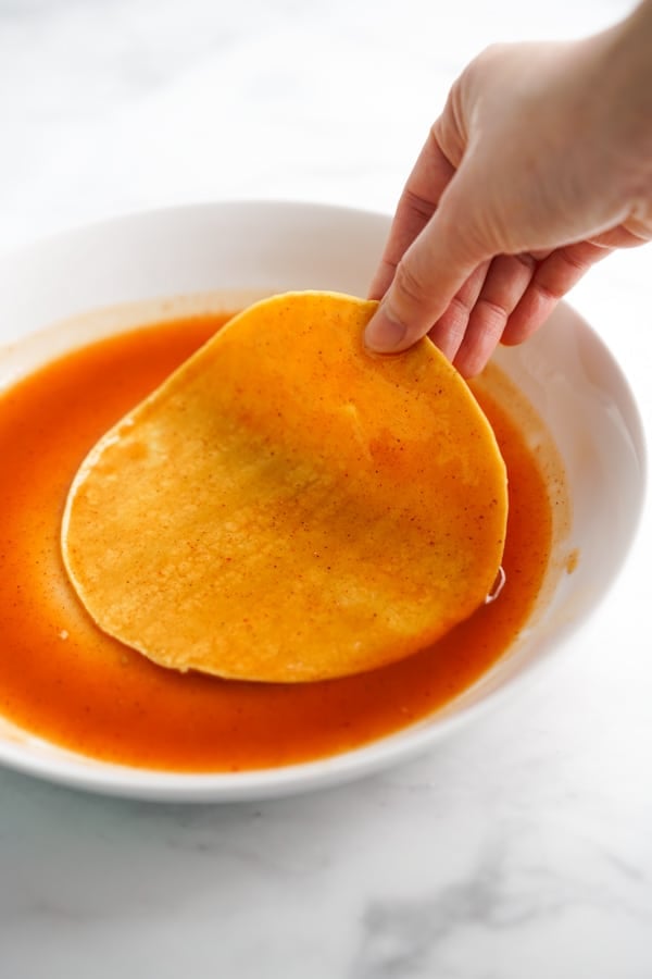 Dip corn tortilla (both sides) into red enchilada sauce